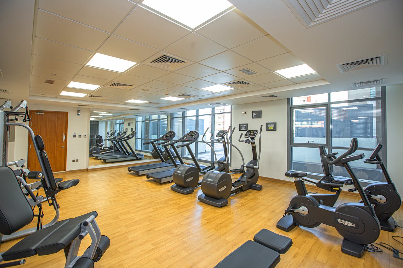 Services Spacious indoor gym with treadmills, stationary bikes, and exercise equipment on a wooden floor.