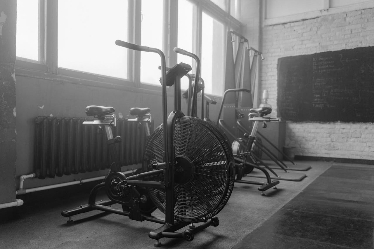 About Black and white gym interior featuring exercise bikes and fitness equipment.